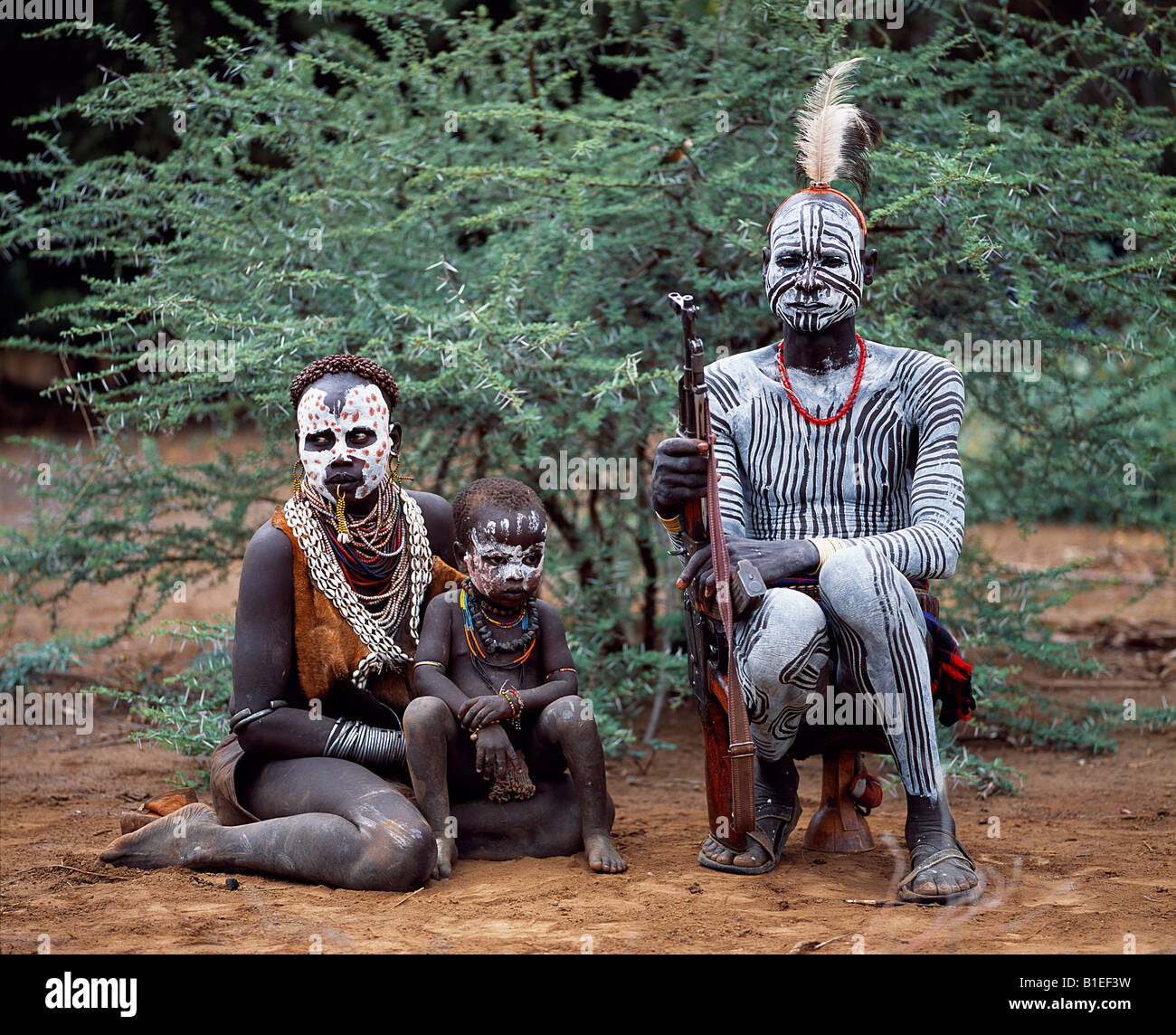 An elder of the Karo tribe sits with his wife and child.  A small Omotic tribe related to the Hamar. Stock Photo