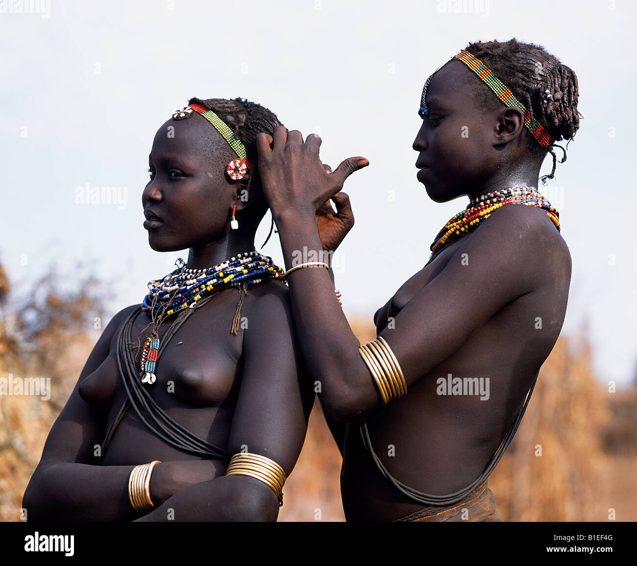 A Dassanech girl braids her sister's hair at her village in the Omo Delta.  Much the largest of the tribes in the Omo Valley. Stock Photo