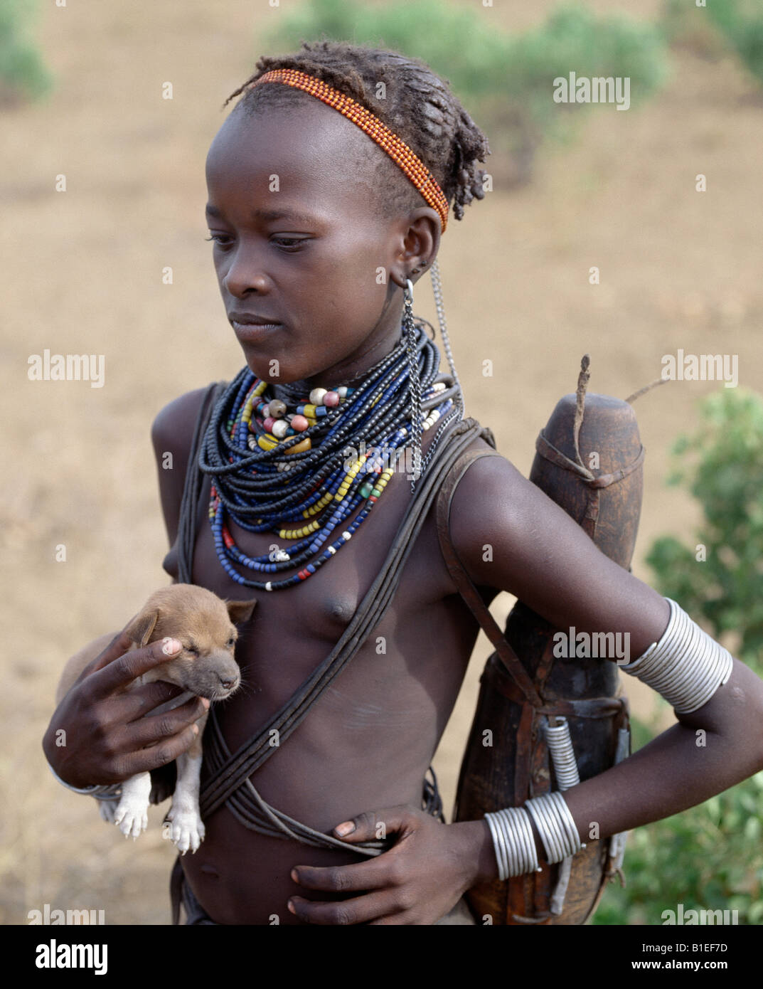 An attractive Dassanech girl holds a puppy. Her adornment is typical of the girls of her tribe. Stock Photo