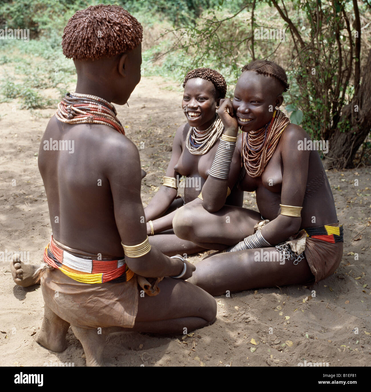 Karo girls chat in the shade of the riverine forest that lines the banks of the Omo River. Stock Photo