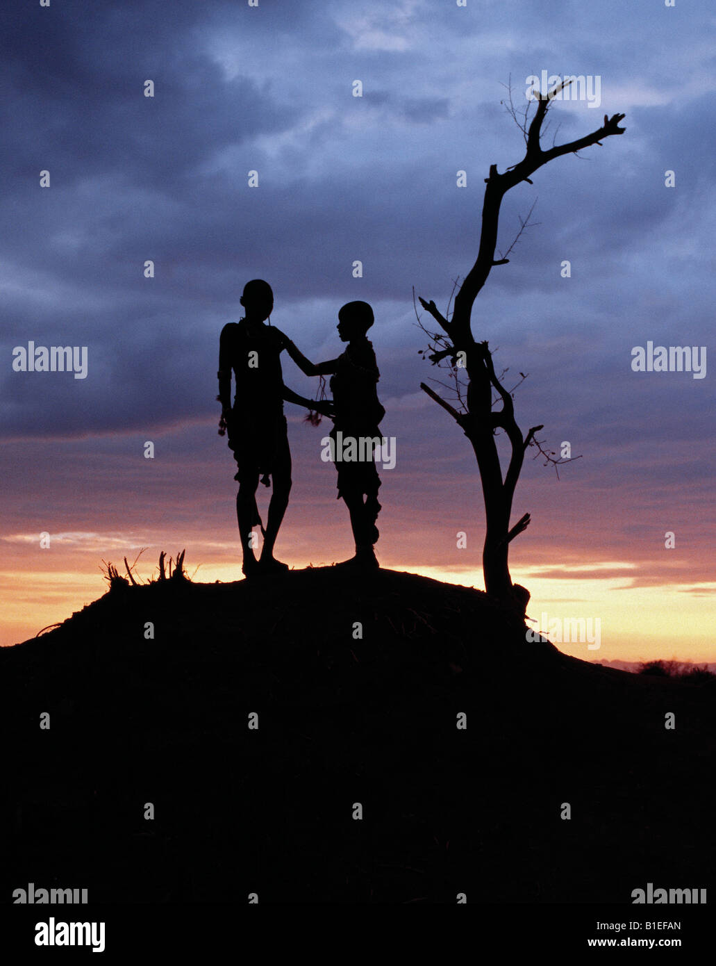 Two Hamar children silhouetted by the setting sun. The Hamar of Southwest Ethiopia are semi-nomadic pastoralists. Stock Photo