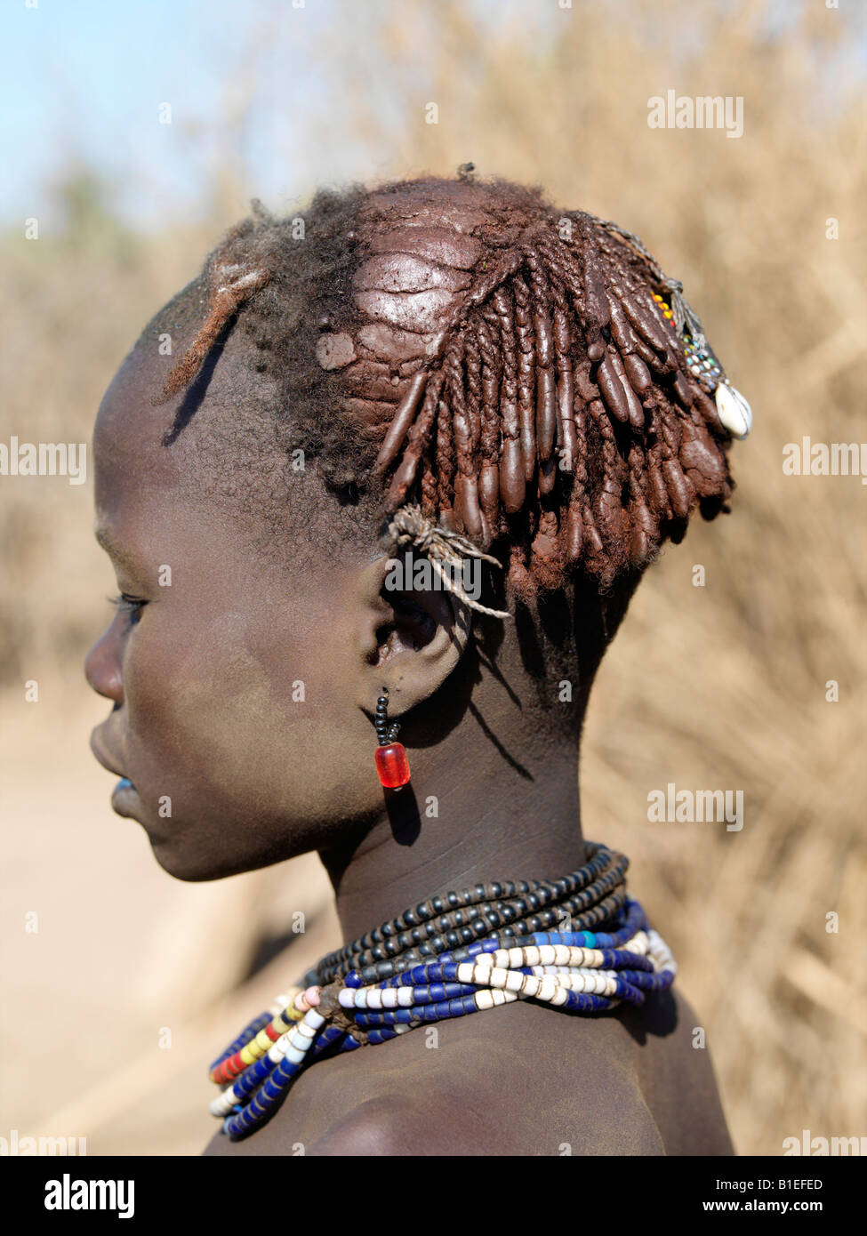 The braided and ochred hairstyle of a Dassanech girl, which has been embellished with beads and cowries. Stock Photo