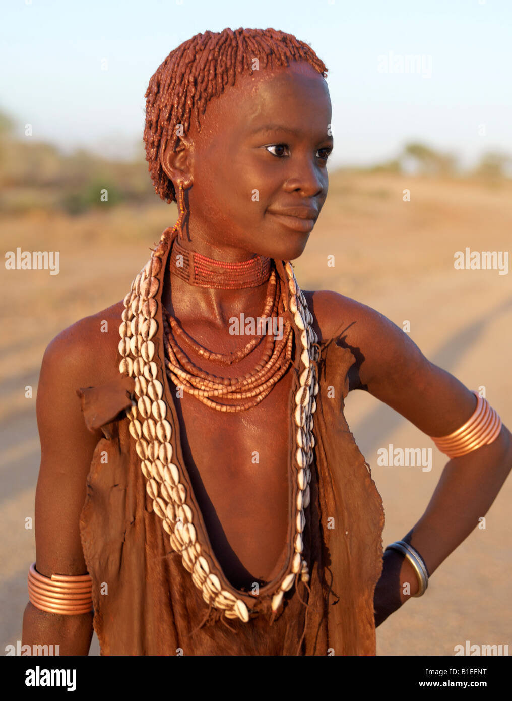 The ochre worn by a pretty young Hamar girl glows deep red in the late afternoon light.The Hamar are semi-nomadic pastoralists. Stock Photo