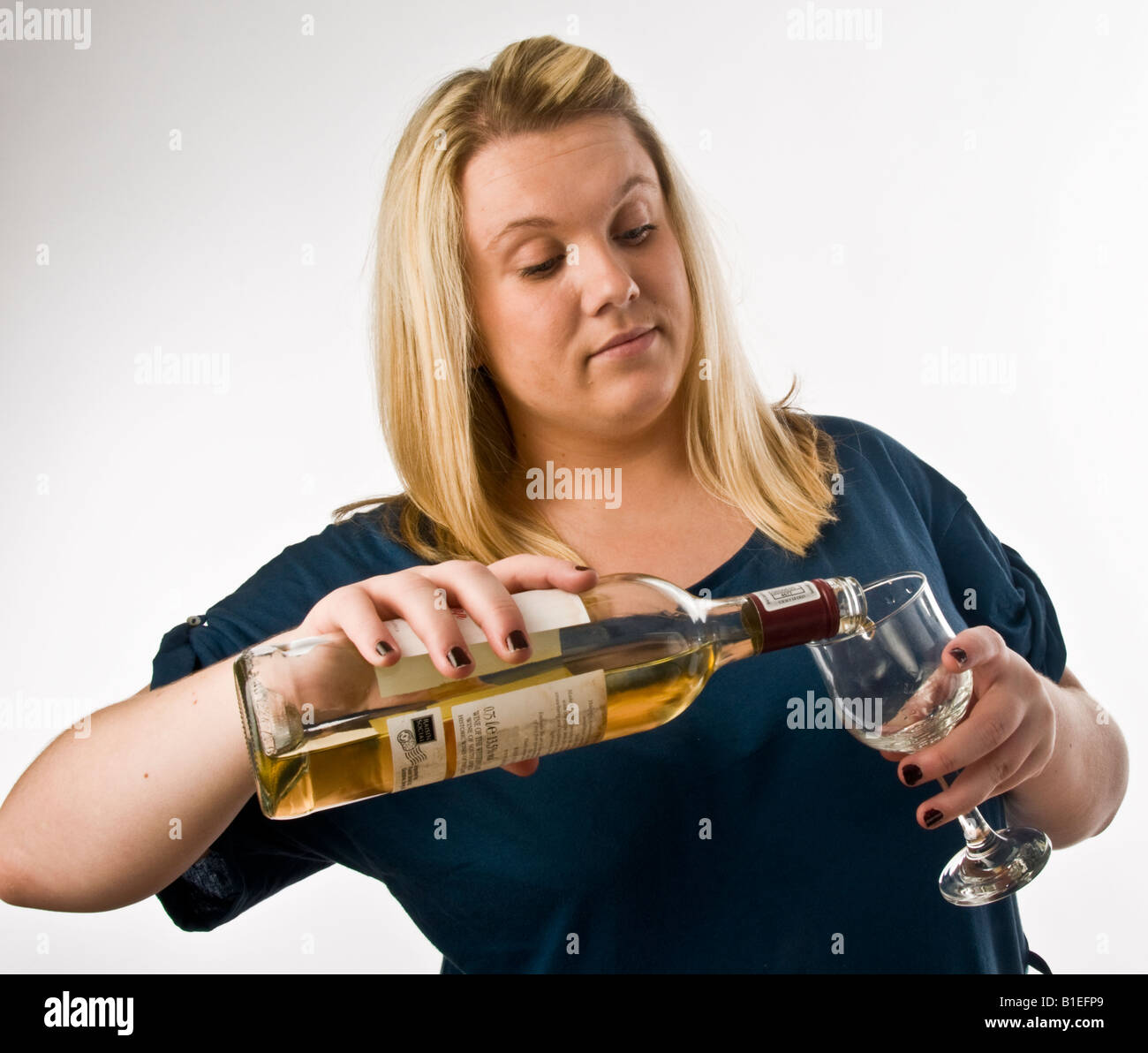 overweight blonde young woman drinking white wine - pouring  a glassful from a bottle Stock Photo