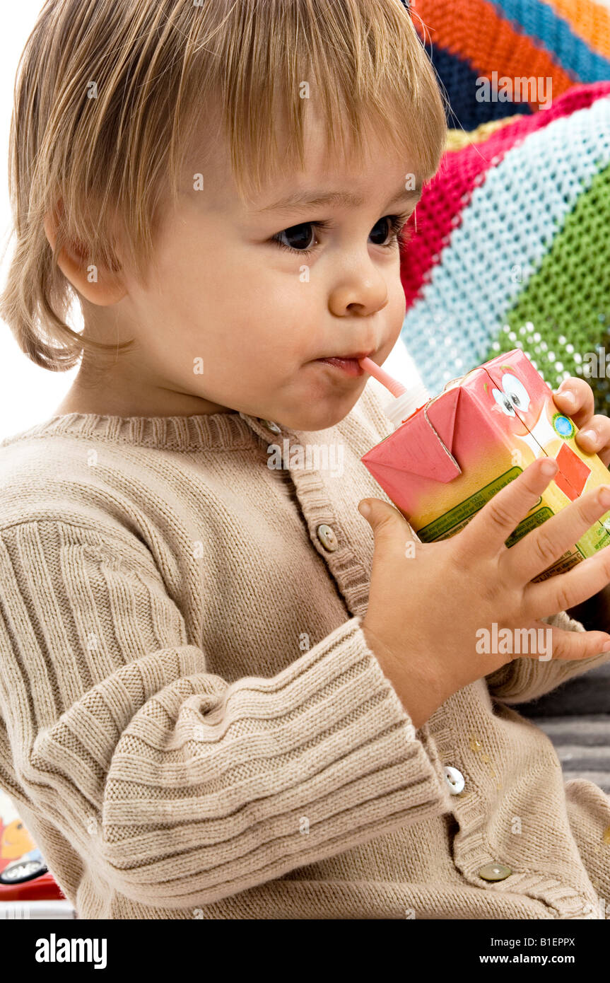 Closeup of a baby boy drinking juice from a carton with a drinking