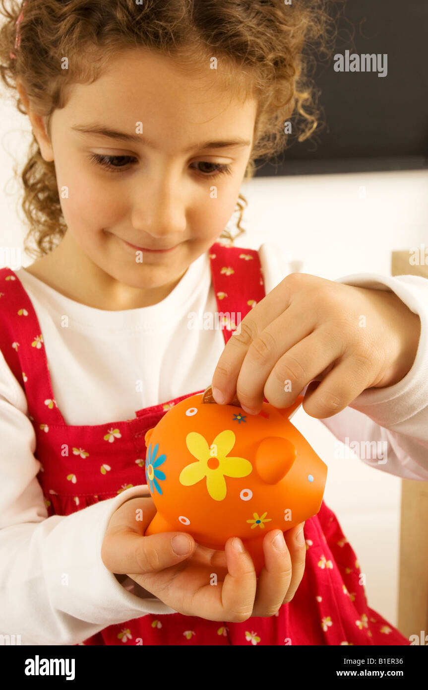 Girl putting a coin into a piggy bank Stock Photo - Alamy