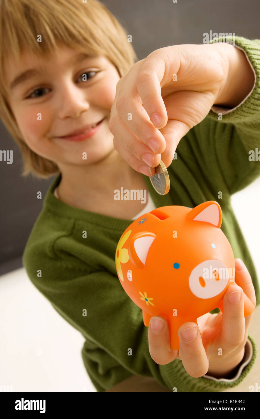 Boy putting a coin into a piggy bank Stock Photo - Alamy