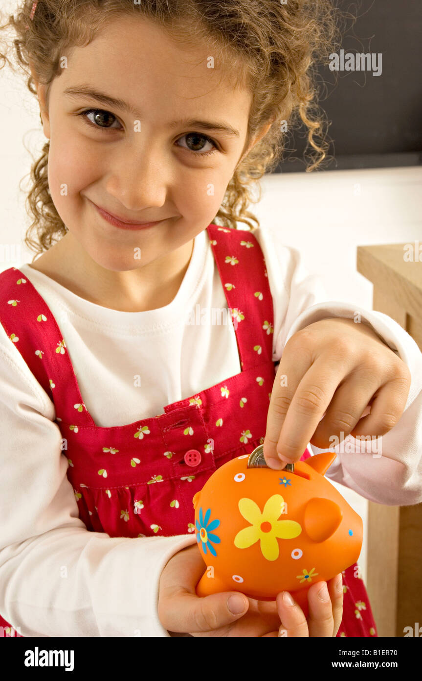 Girl putting a coin into a piggy bank Stock Photo - Alamy