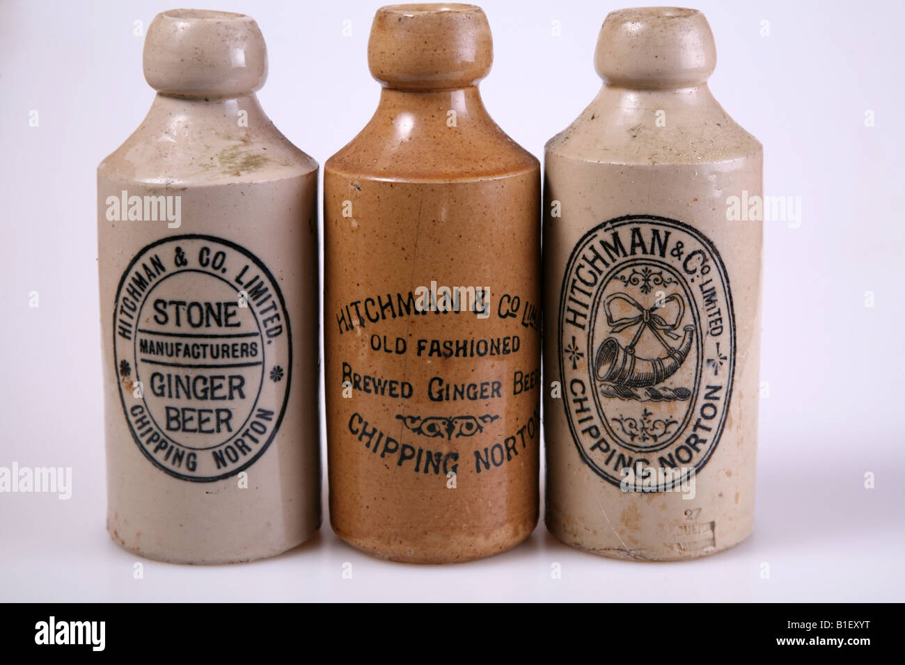A row of three old bottles stood against a white background Stock Photo