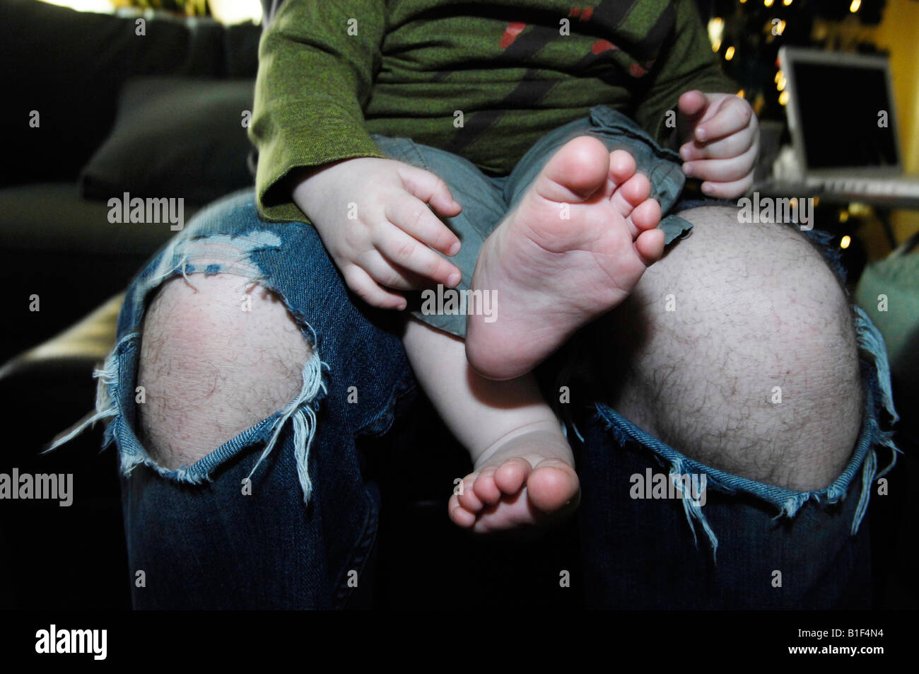 Baby boy on father's lap with ripped jeans Stock Photo - Alamy