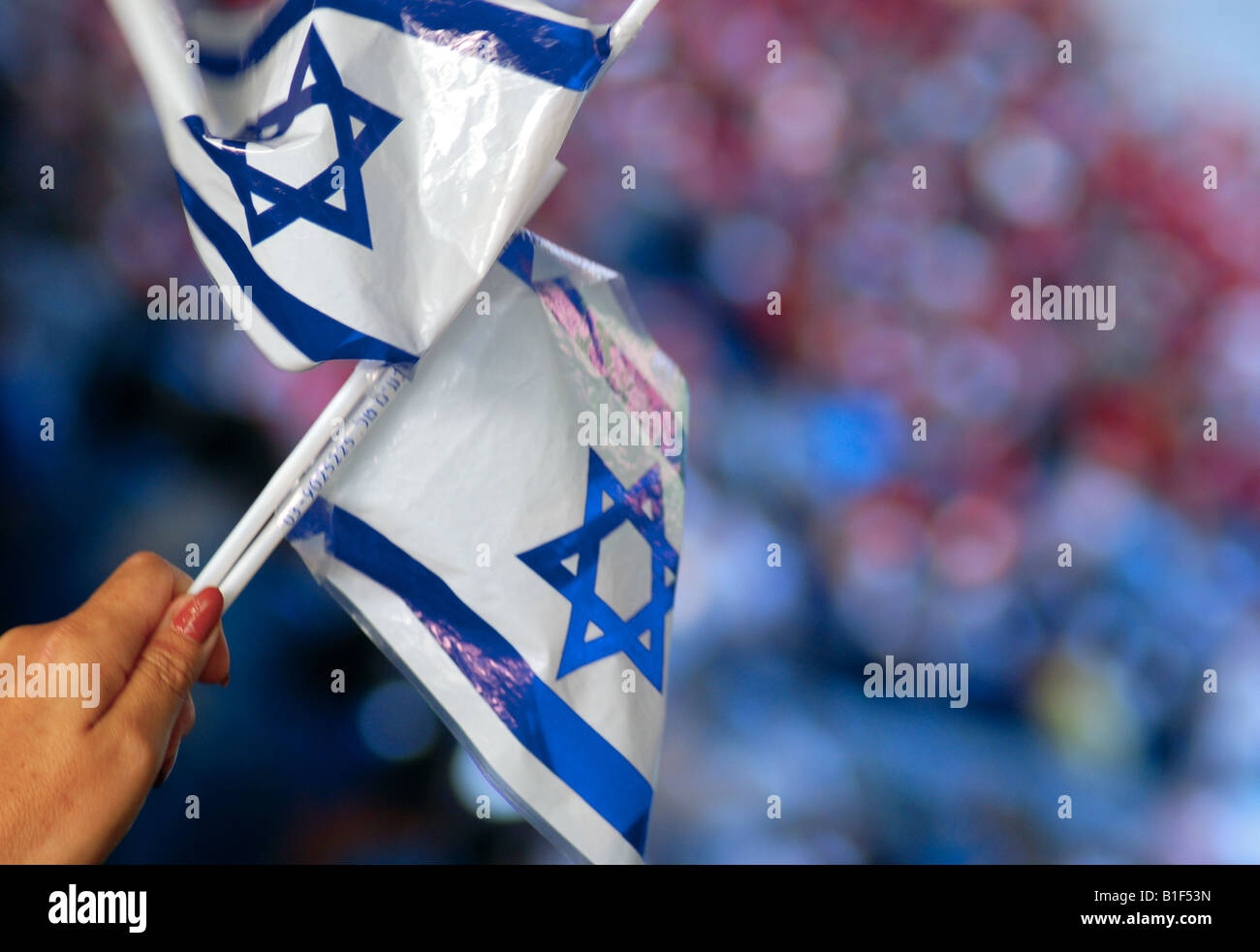 A middle-aged lady waves Israeli flags at an Israel International football match in Basle, Switzerland. Stock Photo
