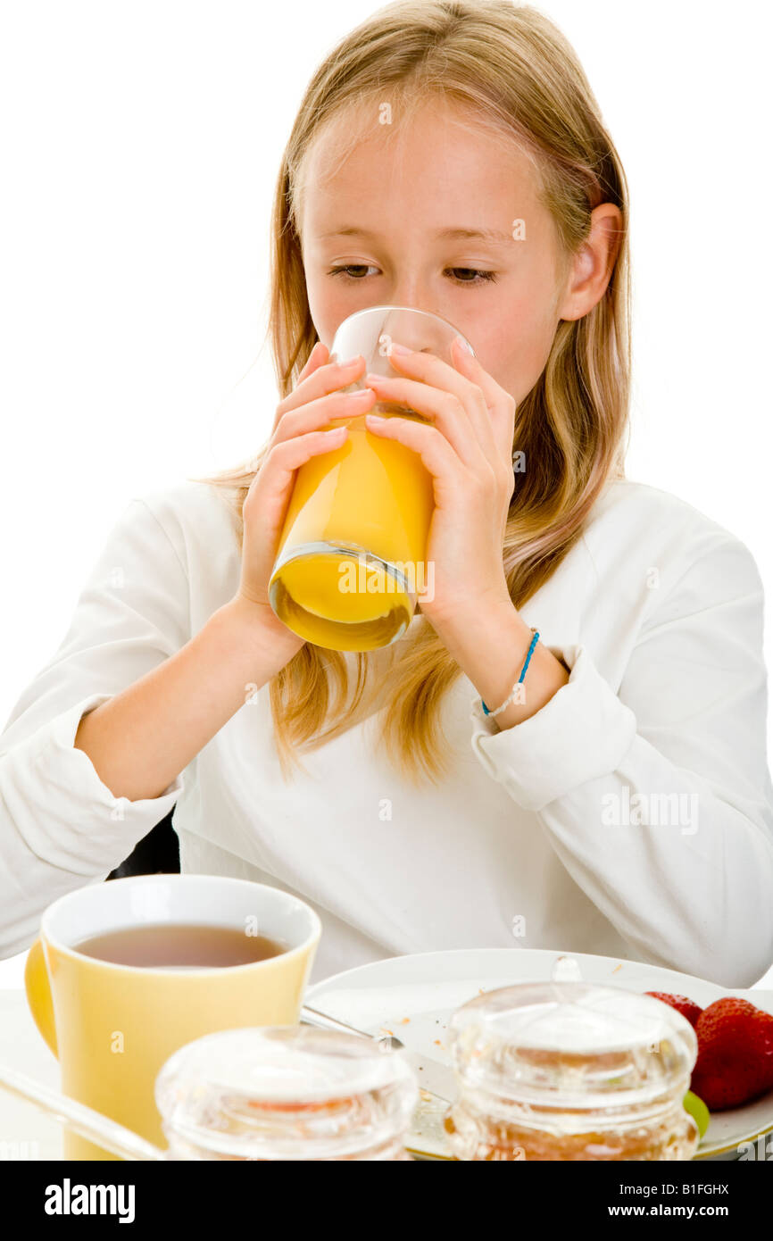 young blonde gril on a breakfast table drinking orange juice Stock Photo