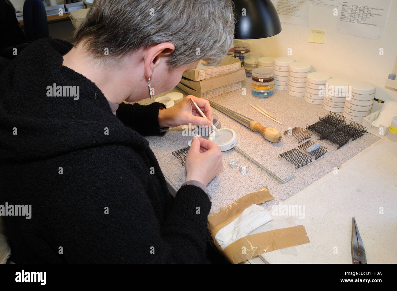 An artisan in Sheila Fleet's Orkney workshop applies enamel to a silver ring. Stock Photo
