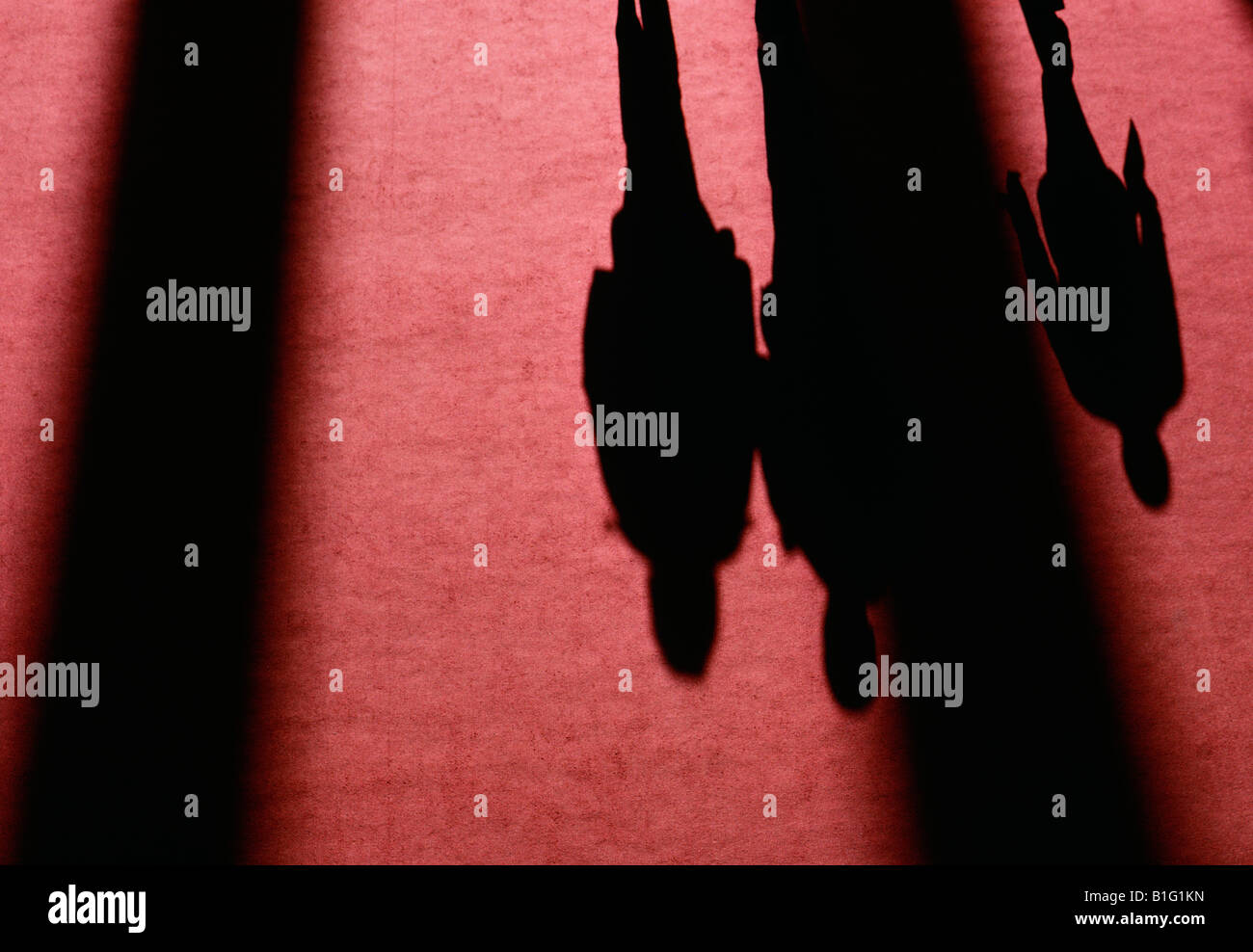 Long shadows of three people cast upon a red carpet Stock Photo
