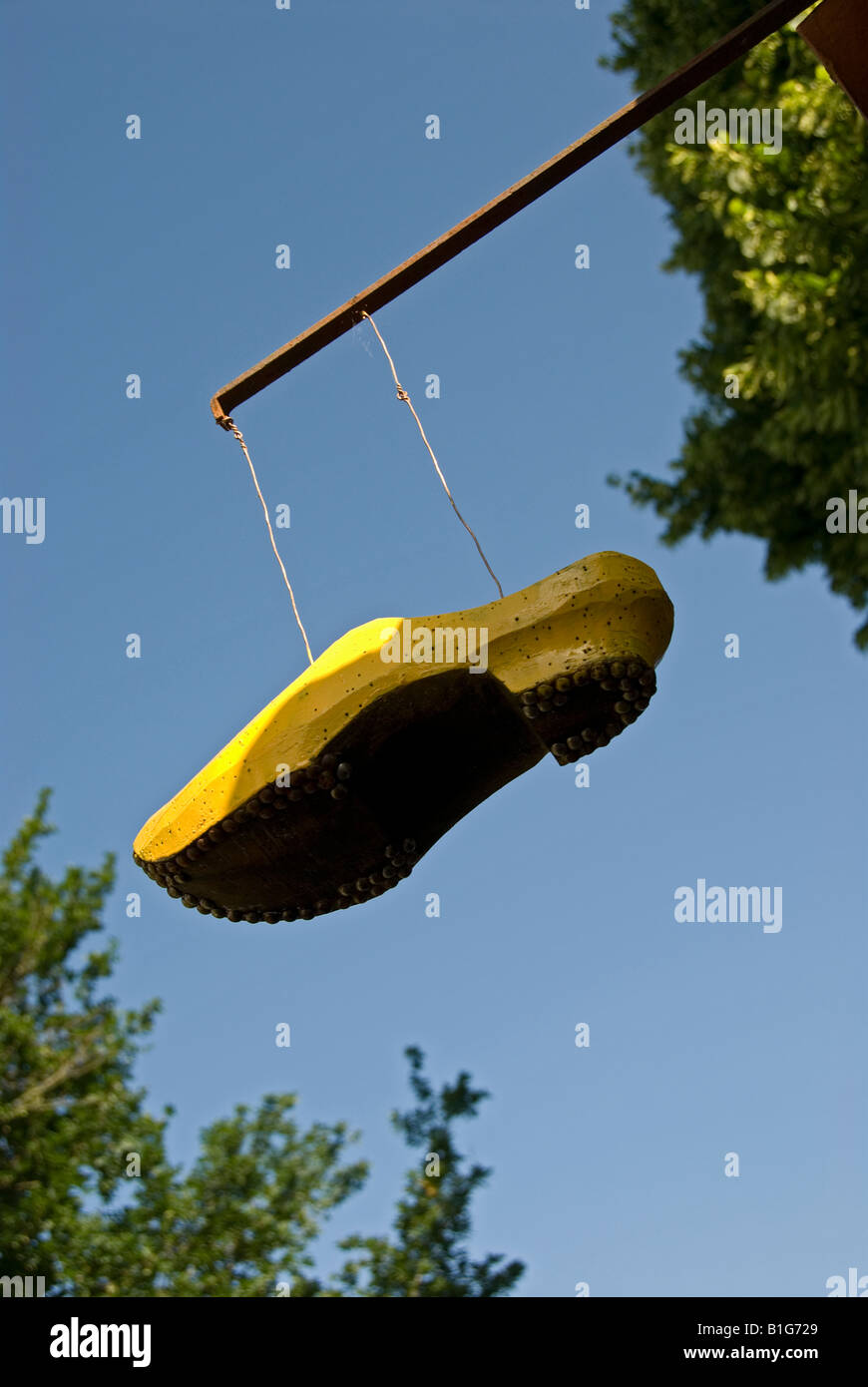 Stock photo of a yellow wooden clog hanging over the netrance to the renovated cobblers in the village of Montrol Senard Stock Photo