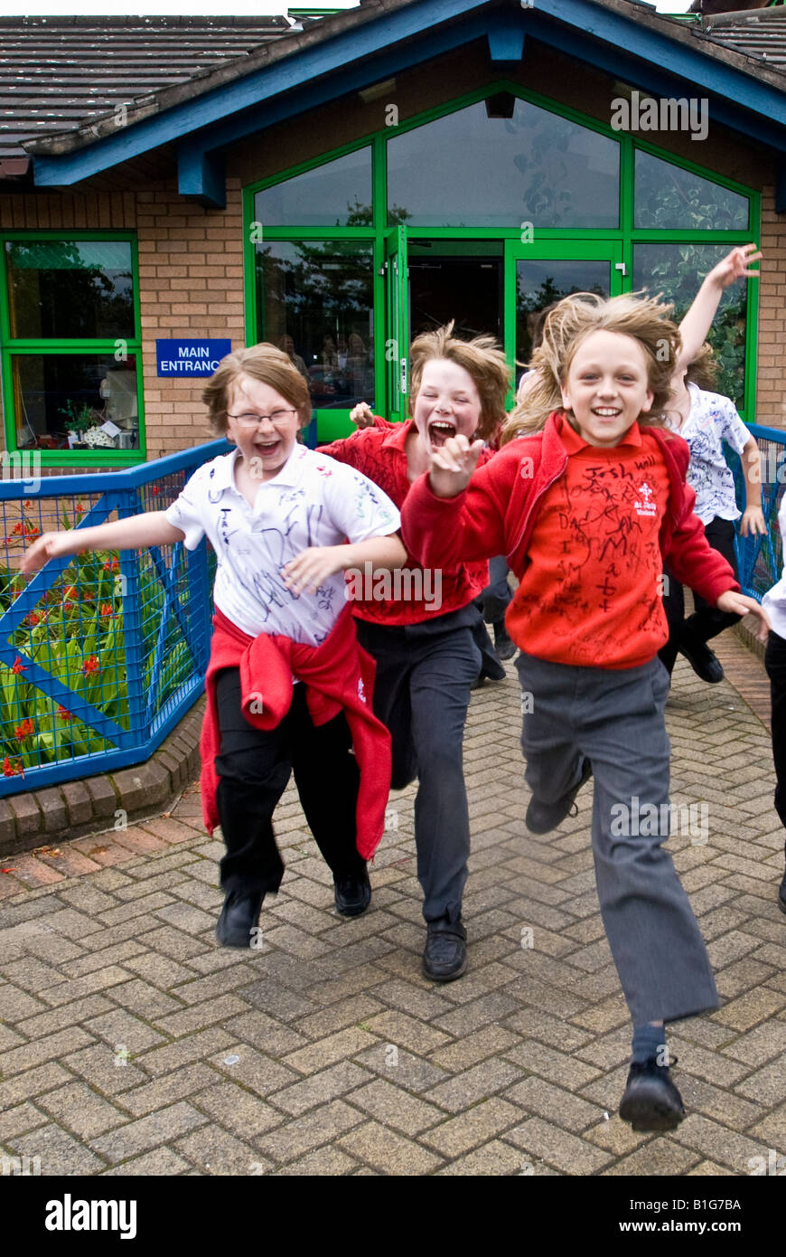 School boys race out of their school at the end of their primary years eager for the summer holidays and Big school. Stock Photo