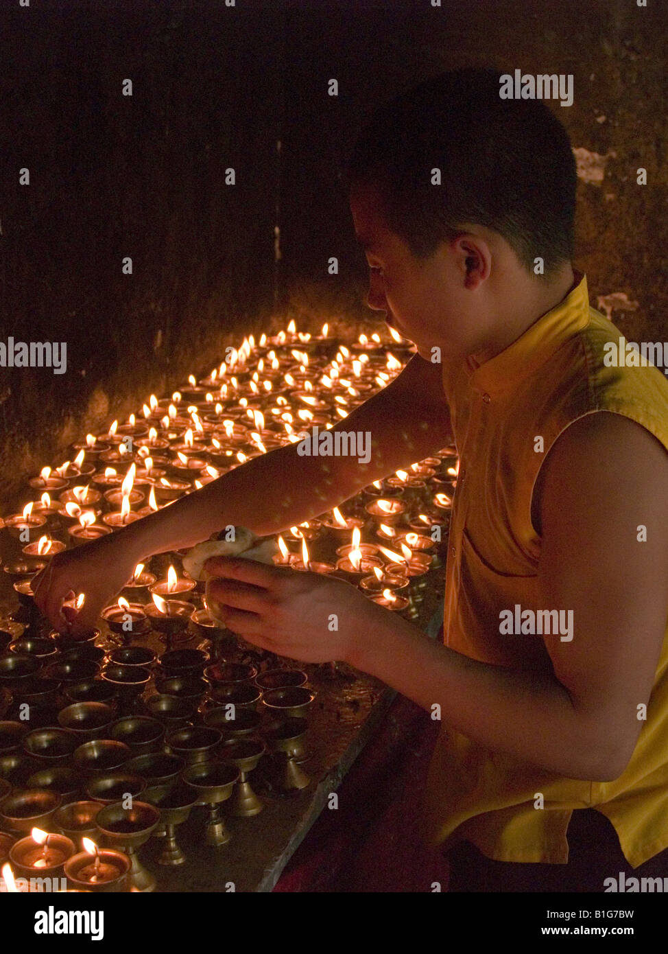 monk lighting butter candles at a Tibetan monastery in Sikkim Stock