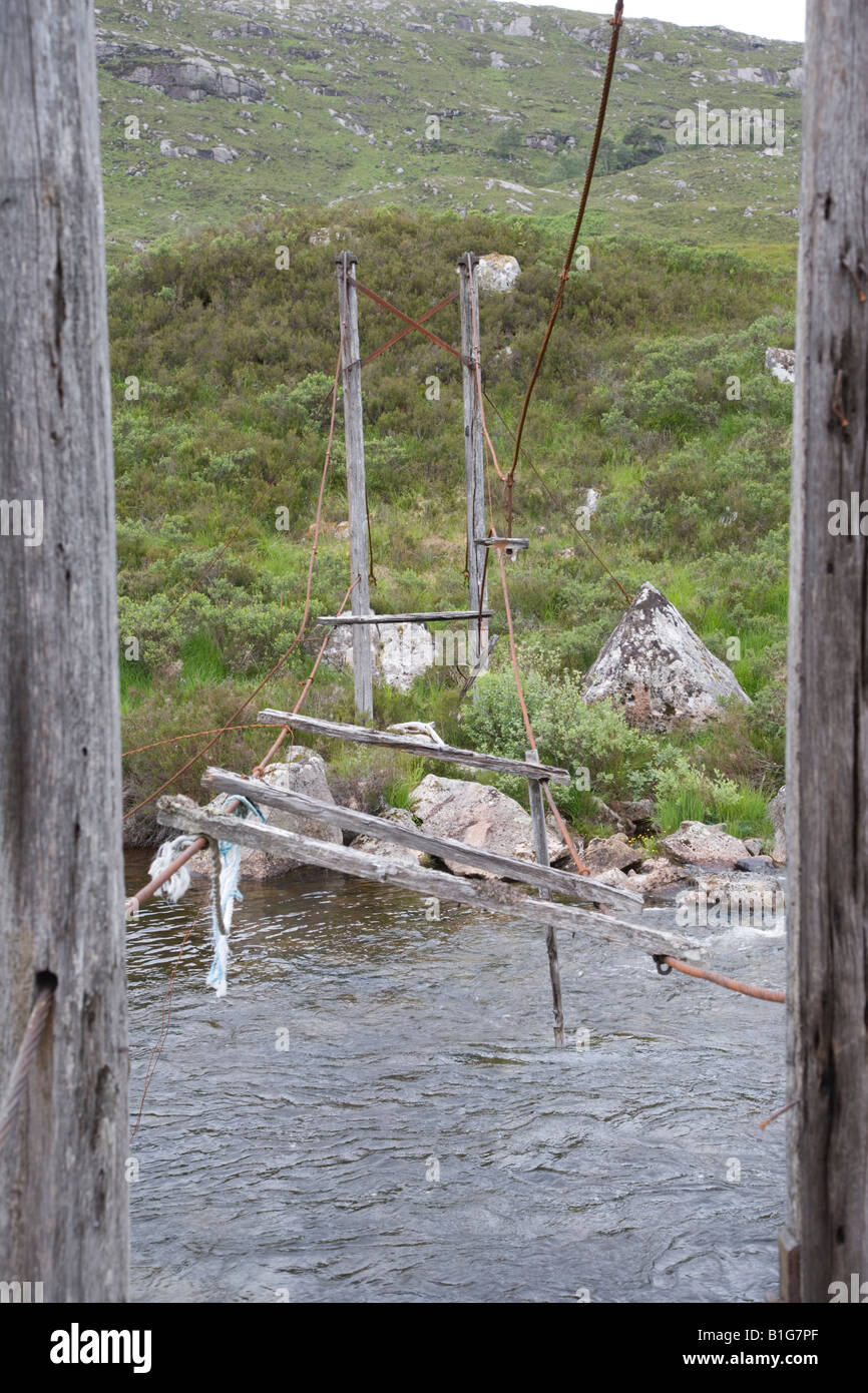 Ruinous simple suspension bridge over river Moriston near dam at Loch