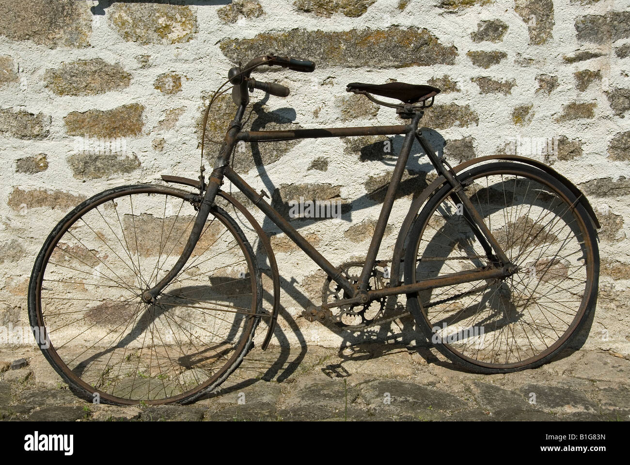 Stock photo of an old broken down bicycle leaning against a stone wall