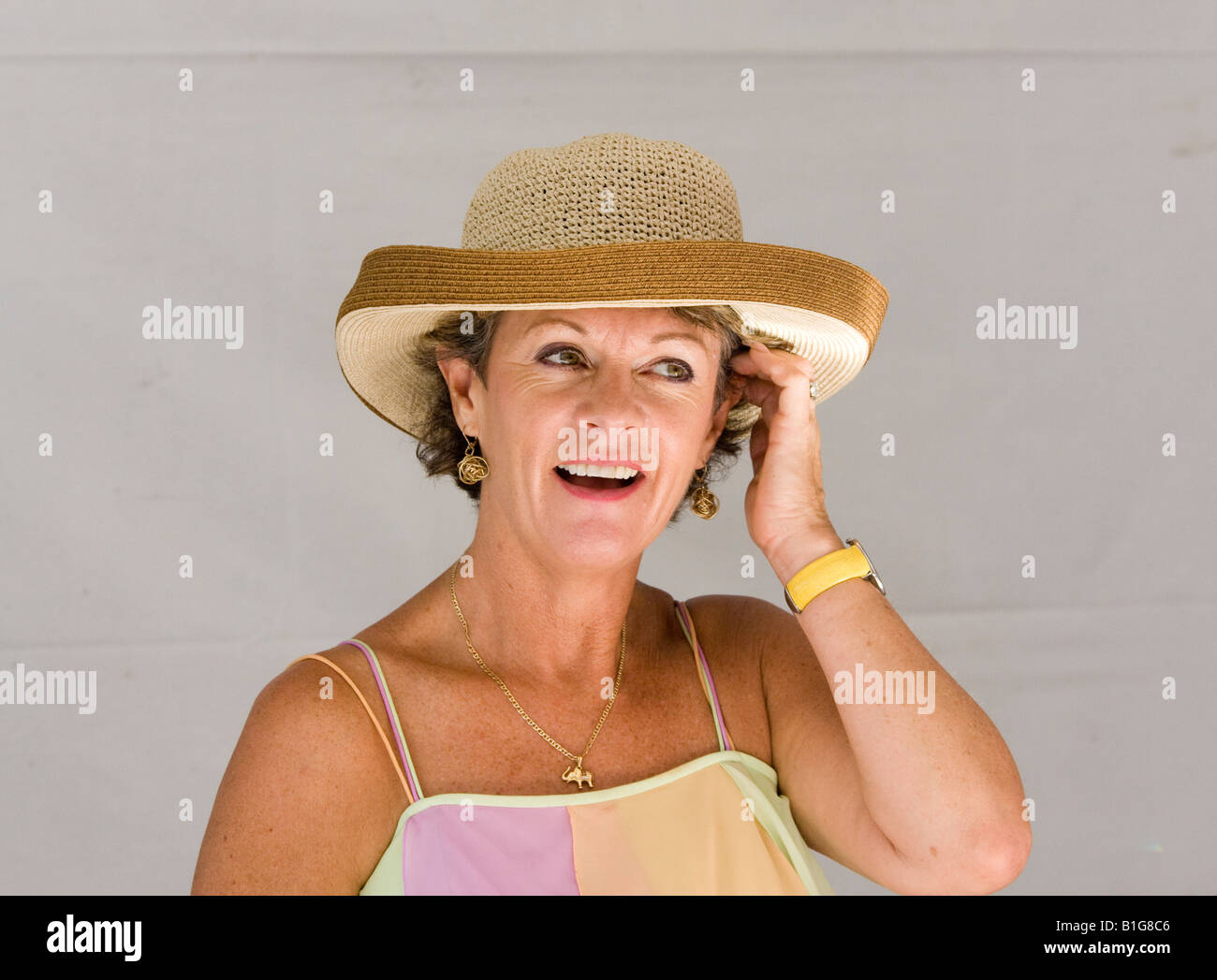 An attractive middle aged woman touches her her while talking to a man off camera during an typical English tea party in Antigua Stock Photo