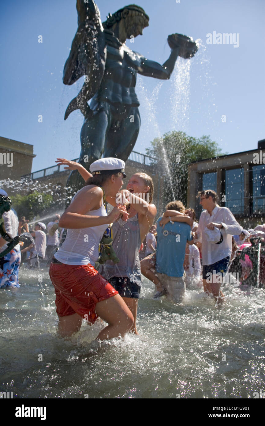High school graduate girls take refreshing splash in the fountain under statue of Poseidon in Gothenburg Stock Photo