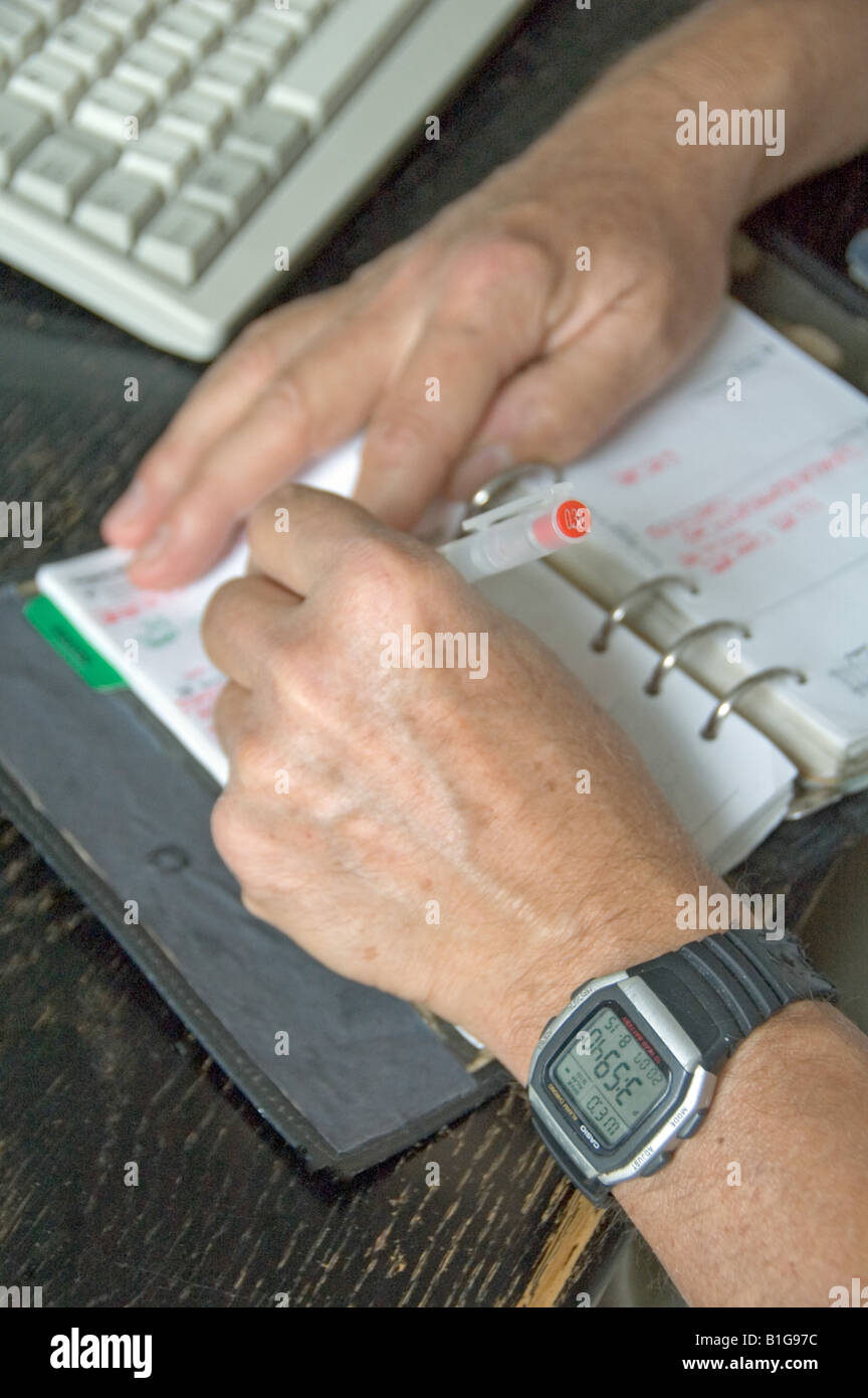 Left handed man writing in diary Stock Photo Alamy