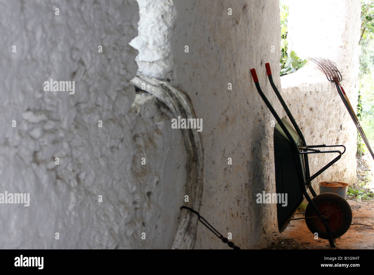 Wheelbarrow and rake against a wall, Fondales village, Andalucia, Spain Stock Photo