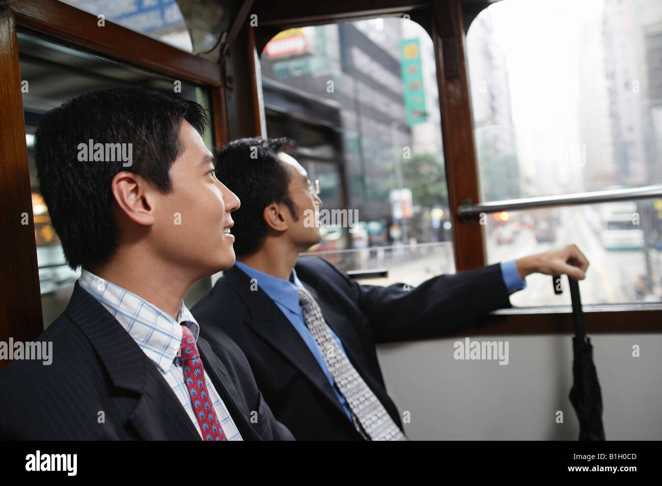 China, Hong Kong, two business men sitting in double Decker tram, side view Stock Photo