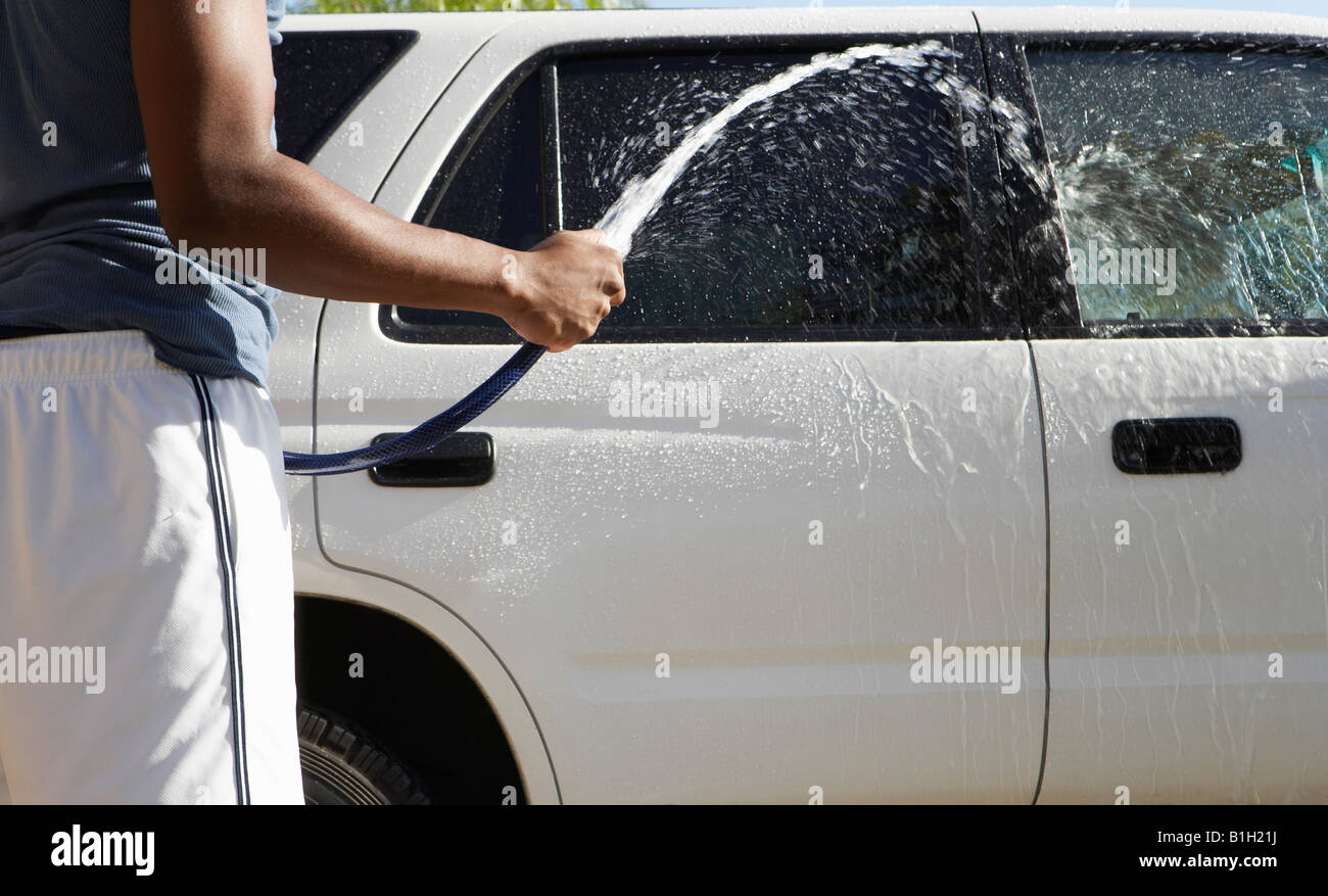 Man spraying car with hose, mid section Stock Photo
