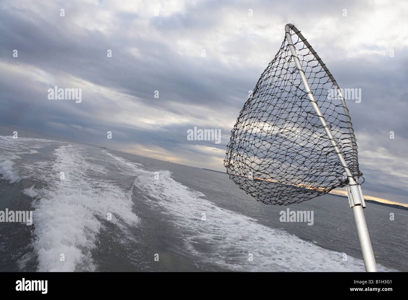 Fishing net sticking on back of speeding fishing boat Stock Photo