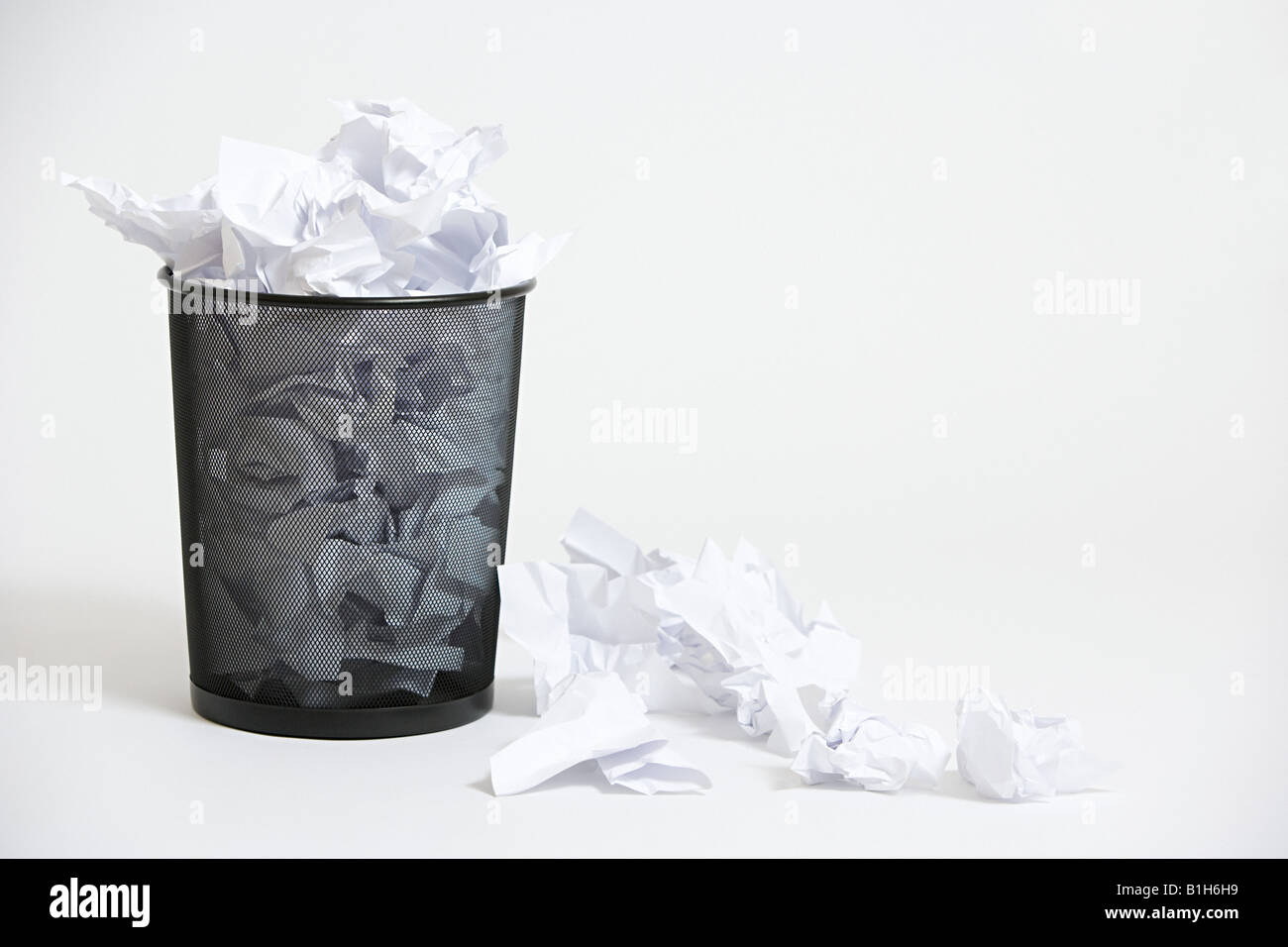 A wastepaper basket with crumpled up paper in it Stock Photo
