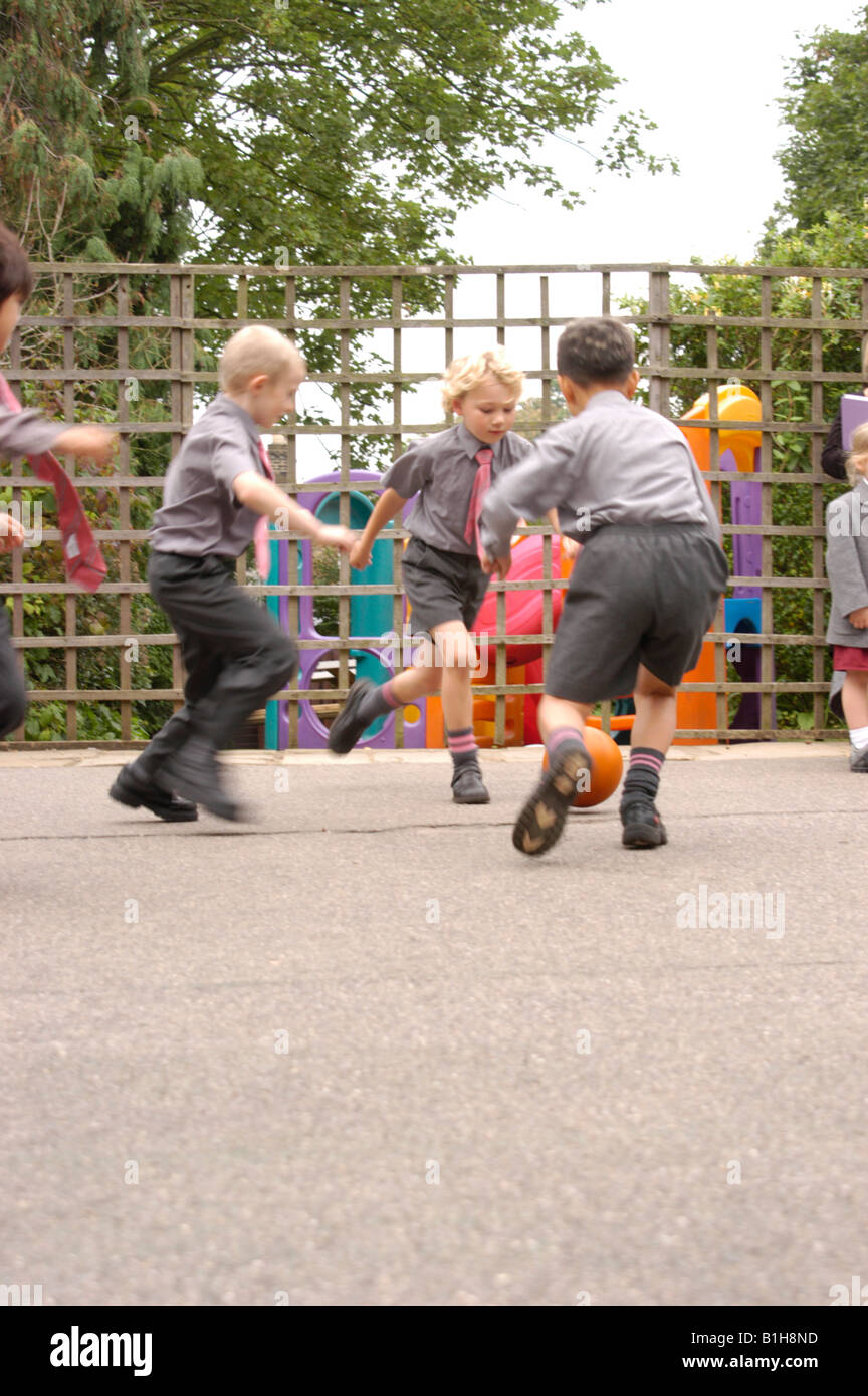 group of boys kicking a ball in a private school playground Stock Photo