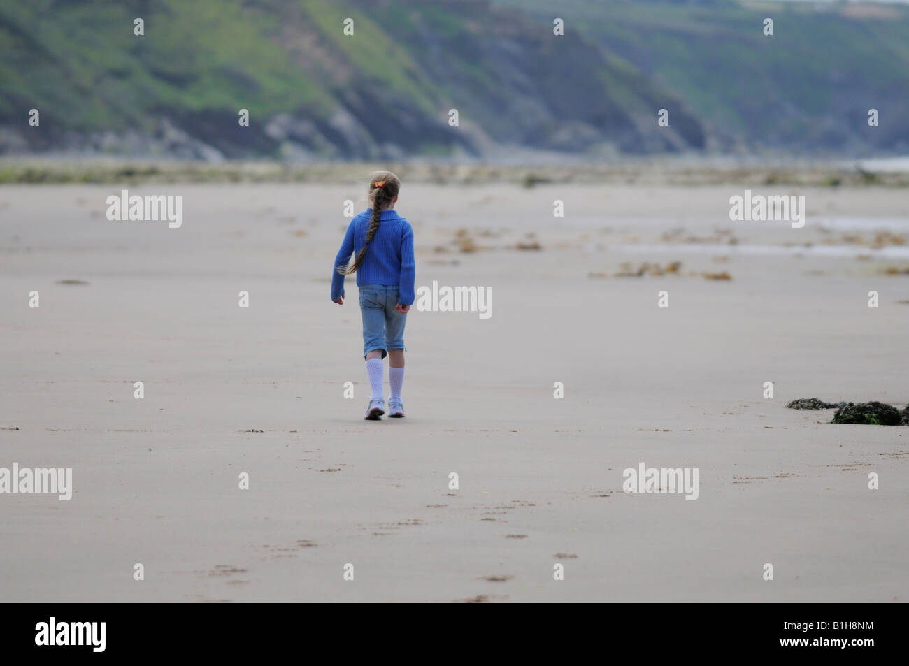 Young girl walking alone on beach Stock Photo