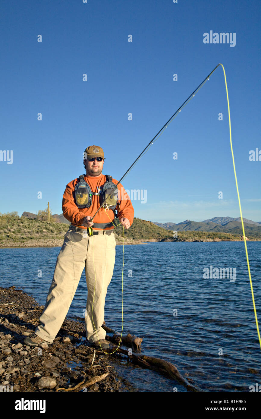 Man fly fishing along the shore of Lake Pleasant in Arizona Stock Photo