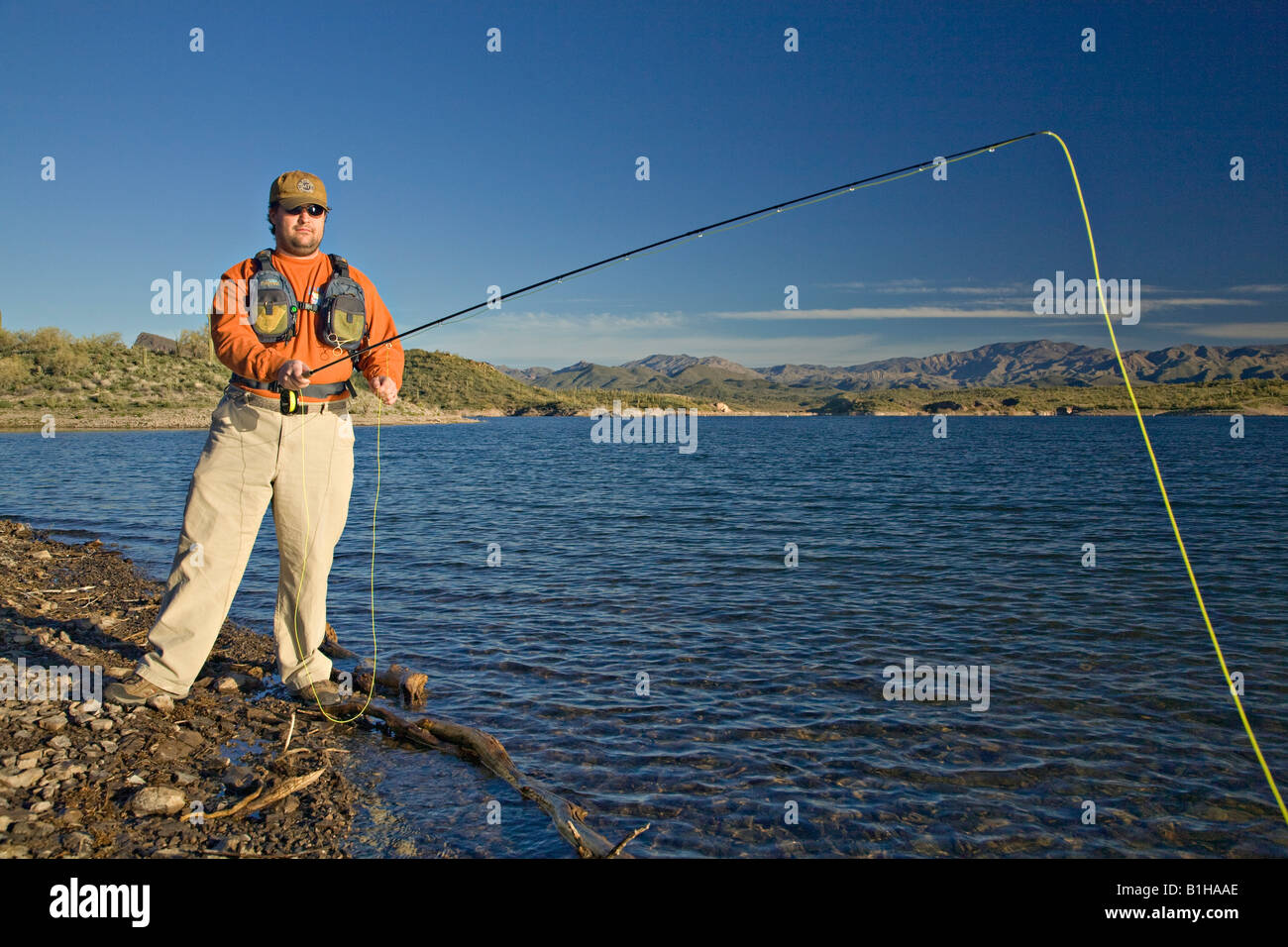Man fly fishing along the shore of Lake Pleasant in Arizona Stock Photo