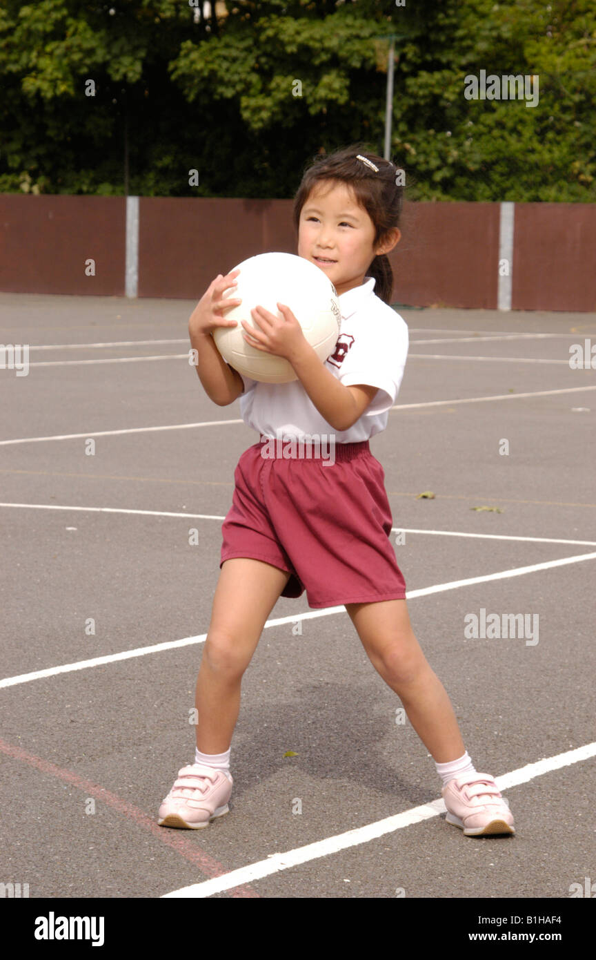 girl holding ball in school yard Stock Photo