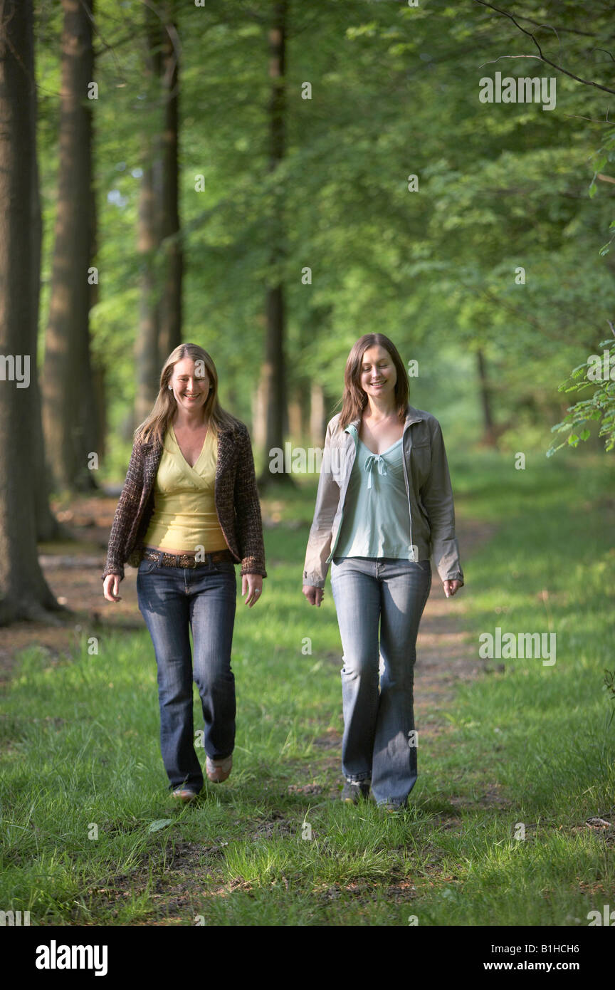 Two young women walking through woods Stock Photo - Alamy