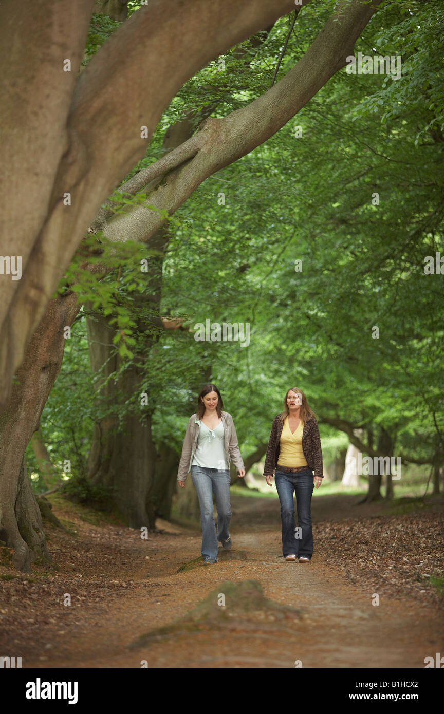 Two young women walking through woods Stock Photo - Alamy