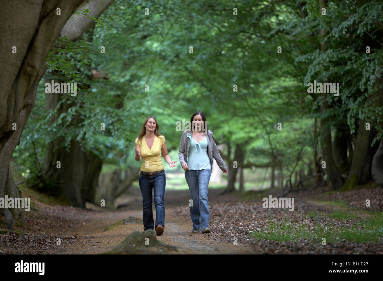 Two young women walking through woods Stock Photo - Alamy