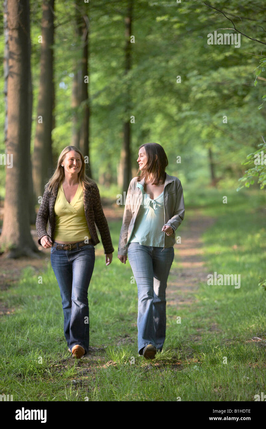Two young women walking through woods Stock Photo - Alamy