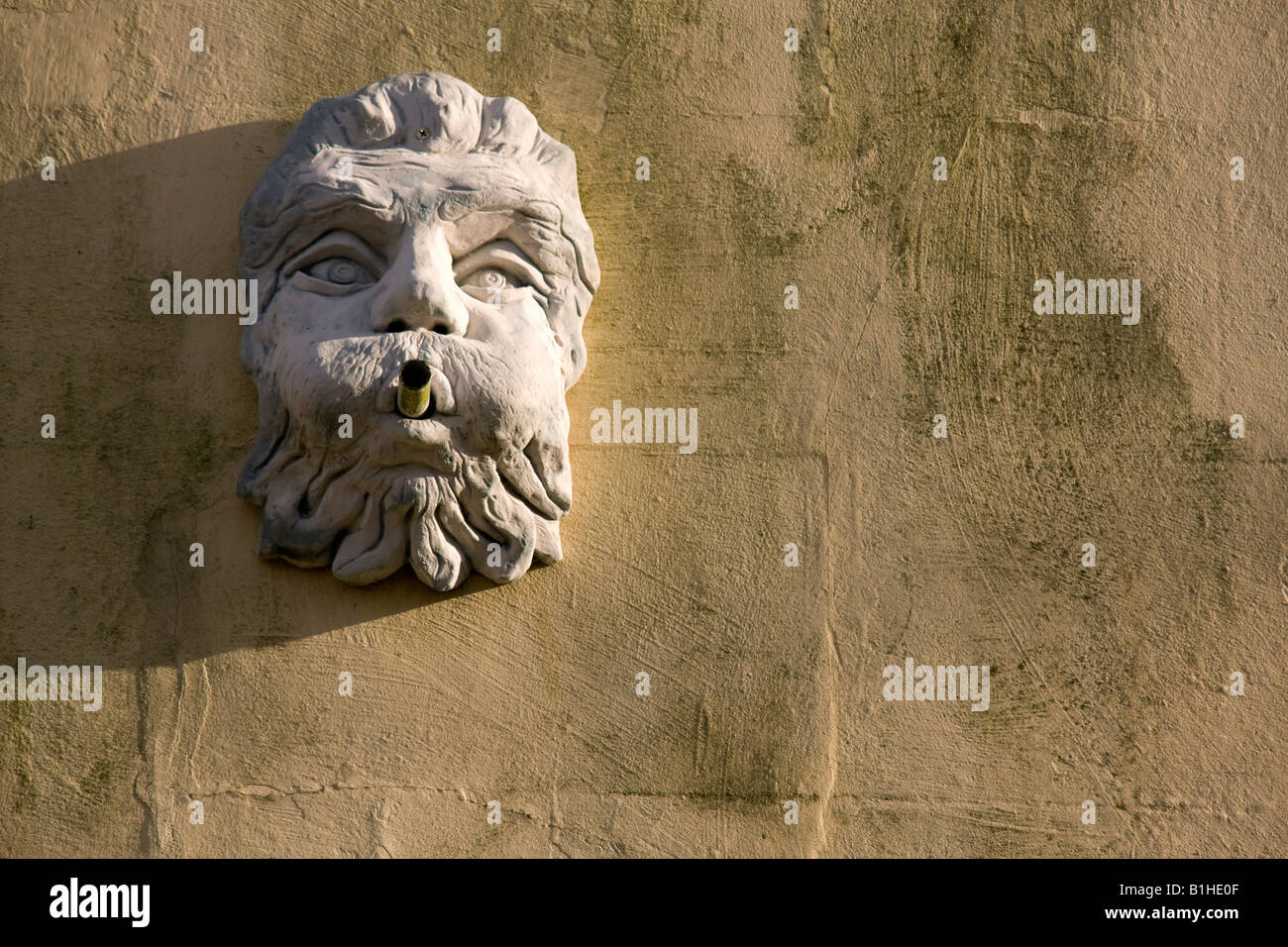 A carving of an ugly face on the wall of a house in a street in Castle Acre a picturesque village in West Norfolk East Anglia Stock Photo