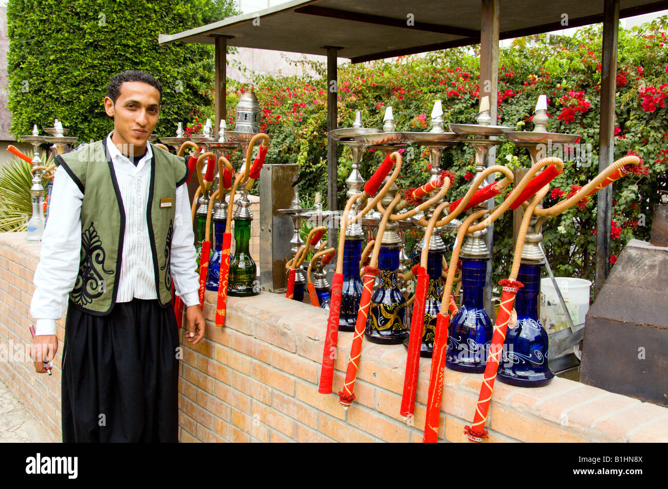 A hotel attendant with sheeshaws at an outdoor lounge at the Sheraton Heliopolis in Cairo Egypt Stock Photo