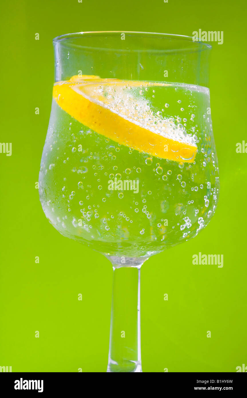 Zitrone in einem Wasserglas mit grünem Hintergrund Stock Photo