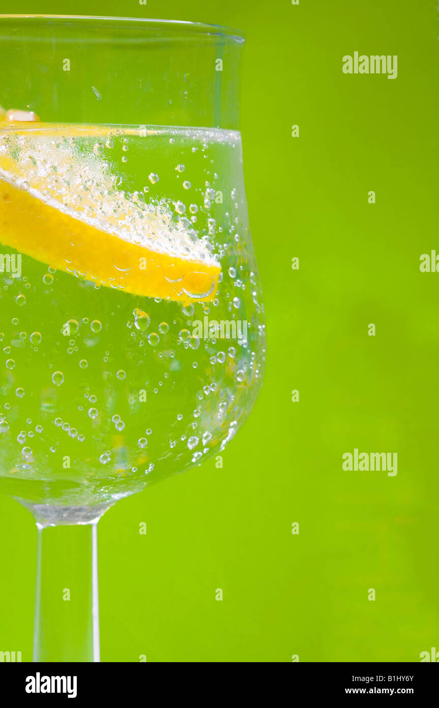 Zitrone in einem Wasserglas mit grünem Hintergrund Stock Photo