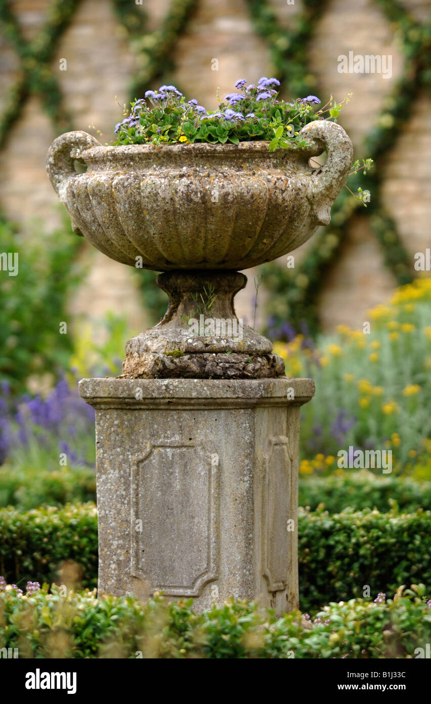 AN ANTIQUE STONE URN IN A WALLED GARDEN WITH IVY TRAINED INTO A LATTICE