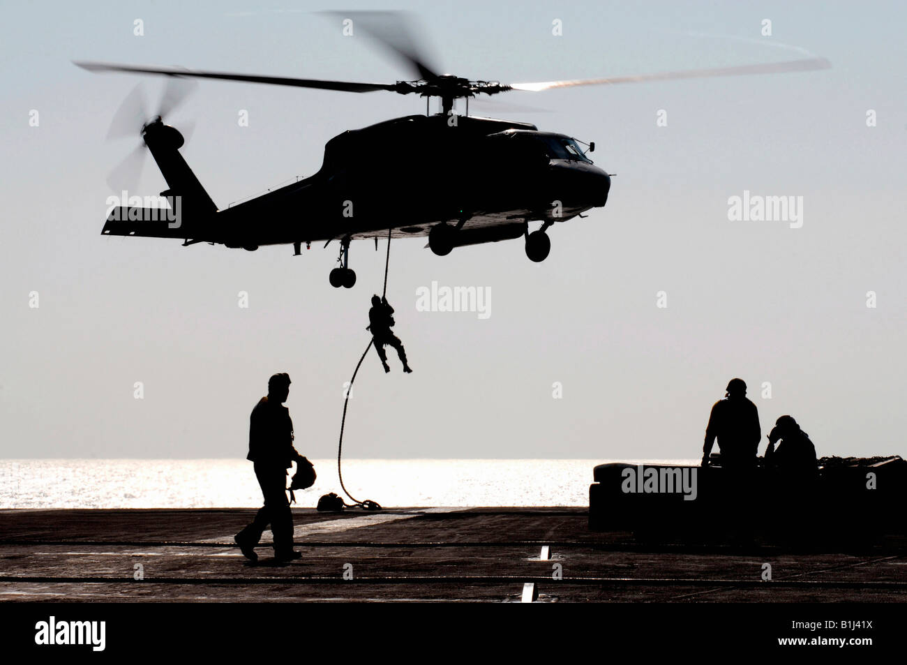 Personnel from Detachment 15 Explosive Ordnance Disposal Mobile Unit One One fast-rope out of an SH-60F Seahawk helicopter Stock Photo