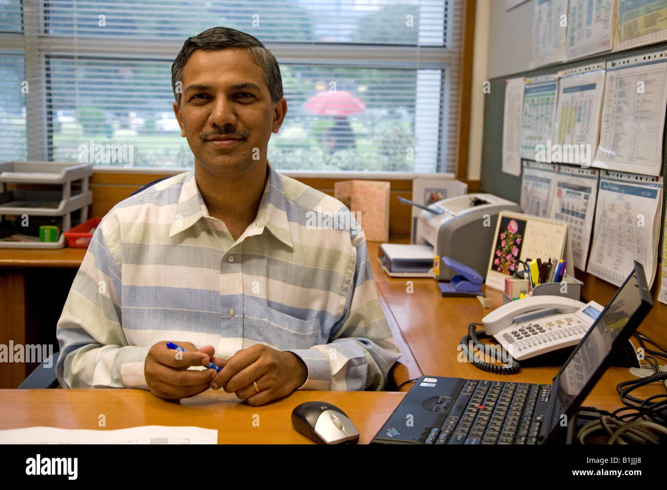A senior manager at his desk in an office in Bangalore, India. The man