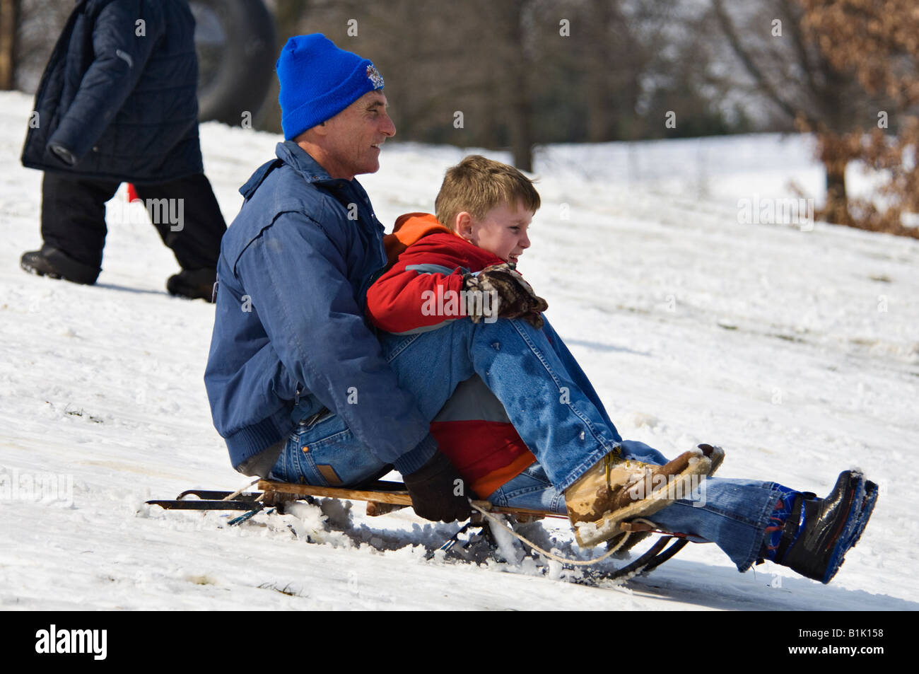 Man and Young Boy Sledding on Snow Covered Hill in Cherokee Park Louisville Kentucky Stock Photo