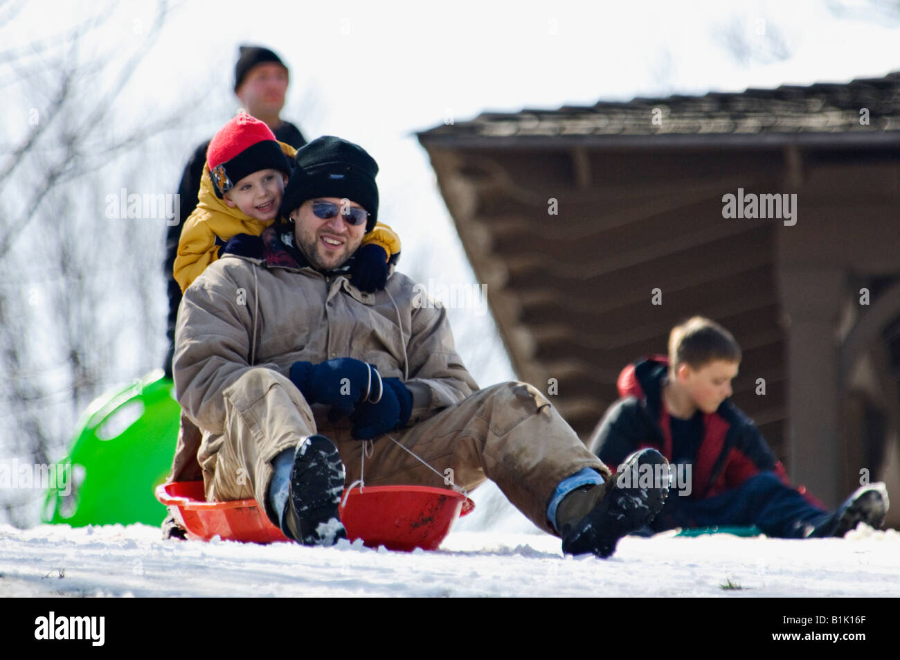 Man and Young Boy Sledding on Snow Covered Hill in Cherokee Park Louisville Kentucky Stock Photo