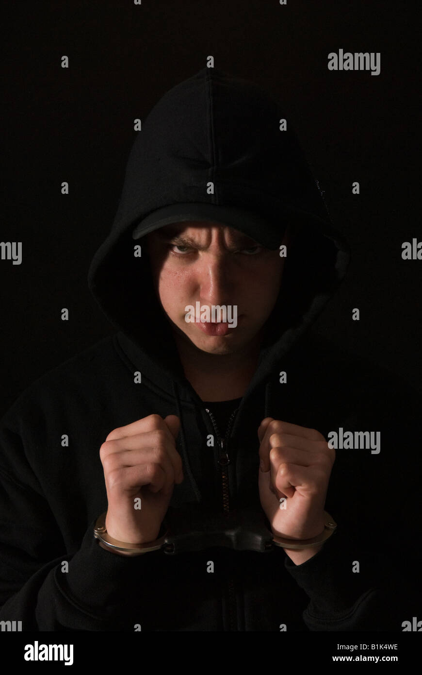 Handcuffed youth wearing black hoody Stock Photo